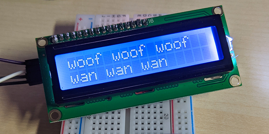 A small 16x2 LCD displaying the text woof woof woof wan wan